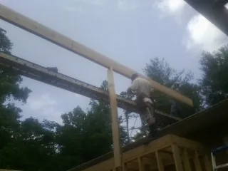 Carpenter setting a ridge beam over a new addition frame — Ice Dam Removal by Roofing Brothers in Gold Creek