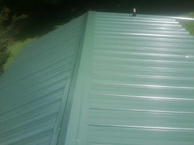 New green metal panels meeting at the ridge of a roof — Flat Roof Repair work by our crew in Gold Creek
