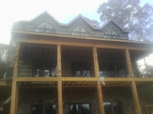 Dormers and porch framing on a large log home under construction — Roof Coating work by our crew in Gold Creek