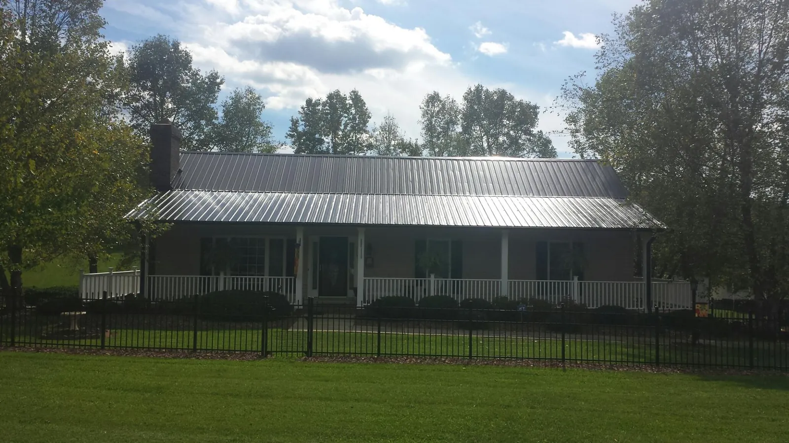 Gray metal roof on a brick ranch with a full width front porch in Gold Creek