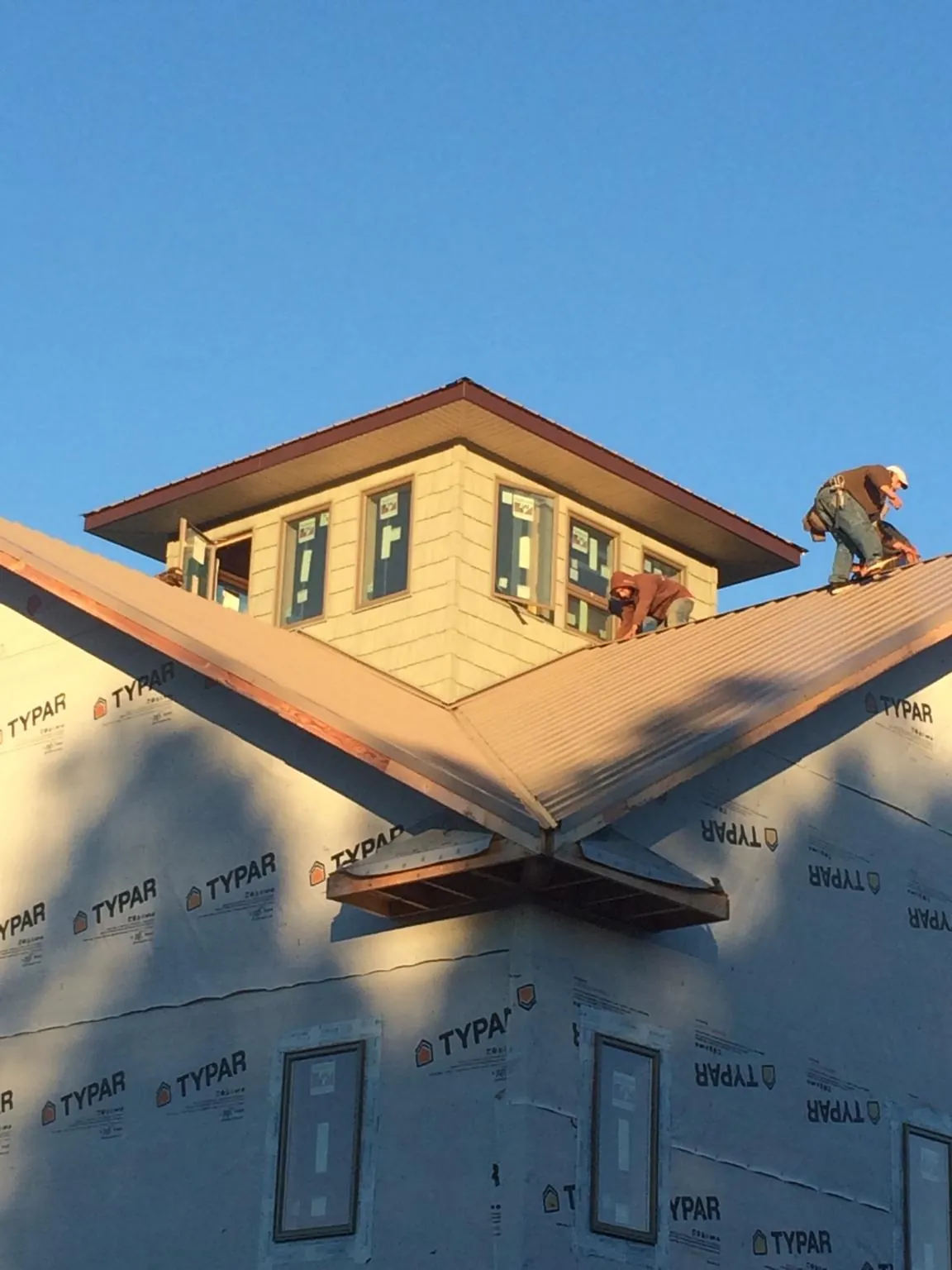 Roofers working around a rooftop cupola on a new metal roof at sunset — Roof Waterproofing in Gold Creek by Roofing Brothers